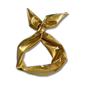 May include: A gold metallic headband with a knotted bow design.