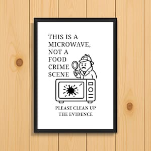 Könnte beinhalten: Ein gerahmter Druck mit schwarzem Rand. Das Bild zeigt einen Schwarz-Weiß-Cartoon einer Mikrowelle mit einem Detektiv, der eine Lupe hält. Der Text lautet: „DAS IST EINE MIKROWELLE, KEIN TATORT. BITTE SÄUBERN SIE DIE BEWEISE.“