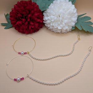 Könnte beinhalten: Zwei Nasenringe aus Gold und Silber mit Perlen- und rosafarbenen Perlenakzenten und einer Perlenkette, die an jedem Ring hängt.