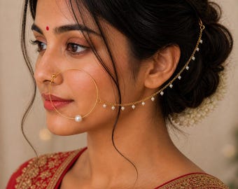 May include: A gold-colored nose ring with a large pearl and a delicate chain with small pearls. The chain attaches to the hair with a small hook. The woman in the image is wearing a red top.