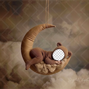 Op de afbeelding: Een bruine teddybeer in een bruine romper slaapt op een bruine halve maan prop. De maan hangt aan een touwtje en de achtergrond is een bruine en witte bewolkte lucht.