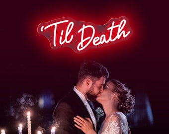 May include: A bright red neon sign displaying the text 'Til Death in a cursive script font. Below the sign, a couple in formal wedding attire are kissing, positioned next to a silver candelabra with five lit candles emitting a soft glow.