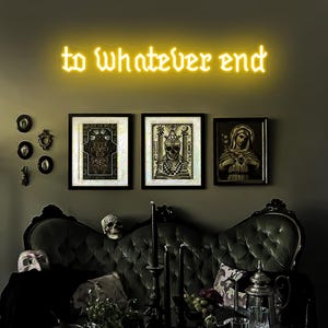 May include: A dark green velvet couch with a neon sign above it that reads "to whatever end". There are three framed pictures on the wall behind the couch, one of which depicts a woman in a long dress holding a heart.
