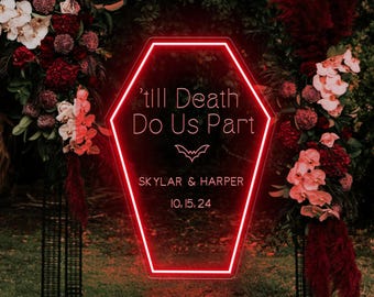 May include: A red neon sign in the shape of a coffin, with the text "'till Death Do Us Part" and a bat symbol. Below the text are the names "Skylar & Harper" and the date "10.15.24". The sign is surrounded by floral arrangements.