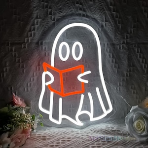 Op de afbeelding: Witte neon-geestcontour die een rood boek vasthoudt. De geest heeft twee grote ogen en een eenvoudige glimlach. Het neonlicht is perfect voor Halloween-decoratie.