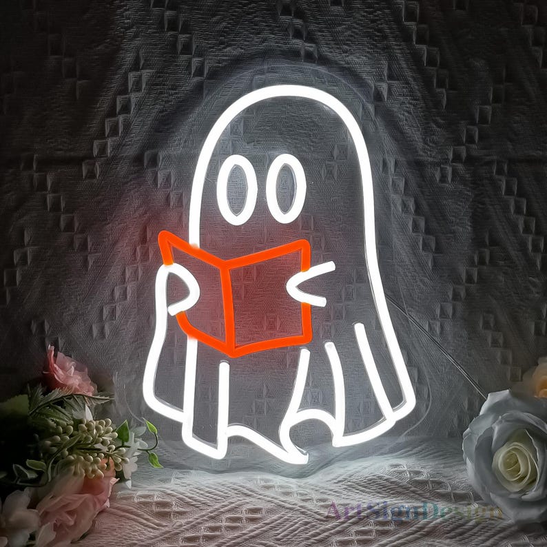 Op de afbeelding: Witte neon-geestcontour die een rood boek vasthoudt. De geest heeft twee grote ogen en een eenvoudige glimlach. Het neonlicht is perfect voor Halloween-decoratie.