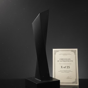 Peut inclure: Sculpture noire, "The Object", avec un design torsadé, sur une base rectangulaire. Un certificat d'authenticité est affiché à côté. Le texte indique "SIGNATURE EDITION | EXCLUSIVE Led Zeppelin".