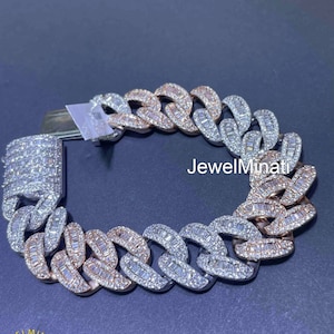 May include: A two-tone, diamond-studded Cuban link bracelet. The bracelet features alternating links of white and rose gold, each encrusted with baguette-cut diamonds. The clasp is also covered in diamonds. The brand name "JewelMinati" is visible.