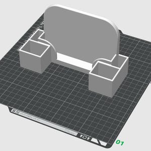May include: A light grey 3D printed desk organiser featuring a central upright rectangular panel with rounded top corners and two square-shaped storage compartments positioned on either side of the base, displayed on a digital grid interface.