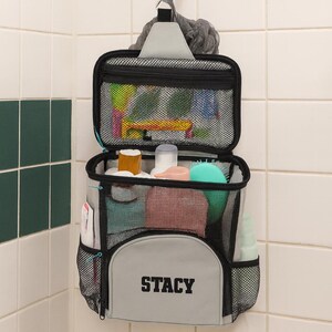 Open mesh toiletry organizer with bottles and grooming tools, suspended in a college shower stall.