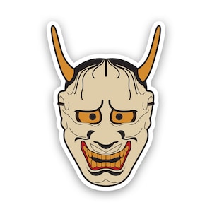 Könnte beinhalten: Eine traditionelle japanische Dämonenmaske mit weißem Gesicht, orangefarbenen Hörnern und einem rot-orangenen Mund. Die Maske hat einen grimmigen Ausdruck mit großen, runden Augen.