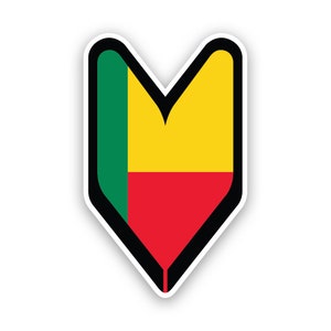 Può includere: Un adesivo verde, giallo e rosso a forma di freccia che punta verso il basso. L'adesivo è una rappresentazione della bandiera del Benin.