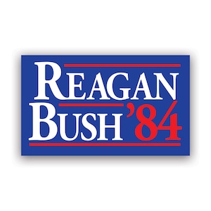 May include: A blue and red political campaign sign with the text "Reagan Bush '84".