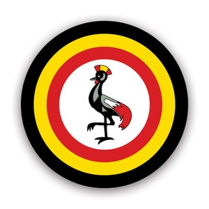 May include: A circular button with a black, yellow, and red concentric ring design. The centre of the button features a white circle with a black and grey crowned crane standing on one leg.