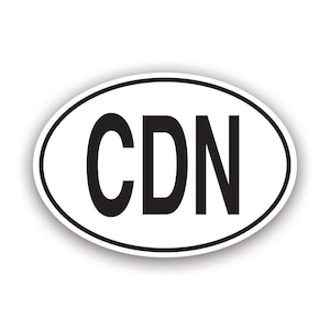 May include: White oval sticker with a black border and the letters "CDN" in bold, black font. The sticker has a slight shadow effect, suggesting it is raised from the surface.