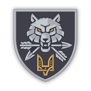 May include: A shield-shaped patch featuring a stylised grey wolf head with yellow eyes, holding two crossed silver arrows in its mouth. Below the wolf, a gold-coloured trident emblem is centred on a dark grey background with a silver border.