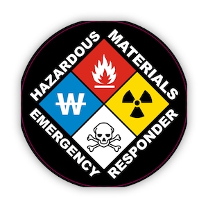 Może przedstawiać: Okrągła naklejka w kolorze czarnym i białym z tekstem "HAZARDOUS MATERIALS EMERGENCY RESPONDER" wokół krawędzi. Środek naklejki zawiera cztery symbole w kształcie rombu, każdy z innym kolorem i symbolem: czerwony z płomieniem, niebieski z "W", żółty z symbolem promieniowania i biały z czaszką i skrzyżowanymi kośćmi.