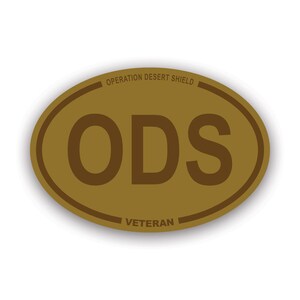 May include: A brown oval sticker with the text "Operation Desert Shield" and "Veteran" at the top and bottom, respectively. The text "ODS" is in the center of the sticker.