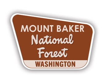 May include: A brown and white sign with the text "Mount Baker National Forest Washington" in a retro style.