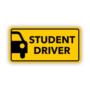 Könnte beinhalten: Ein rechteckiges gelbes Schild mit schwarzem Rand, das auf der linken Seite eine schwarze Silhouette eines Autos und auf der rechten Seite den Text STUDENT DRIVER in fetten schwarzen Großbuchstaben zeigt, konzipiert für gute Sichtbarkeit.
