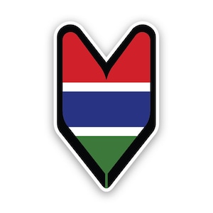 Può includere: Un adesivo a forma di cuore rosso, blu e verde con un bordo bianco. L'adesivo ha la forma di un 'marchio per principianti' giapponese e presenta i colori della bandiera gambiana.