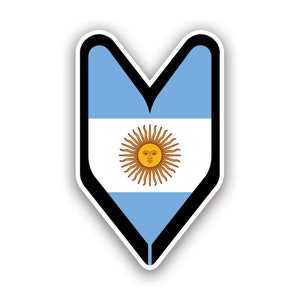 May include: A blue and white sticker with a black outline in the shape of a V. The sticker features the flag of Argentina, with a yellow sun with a face in the center.