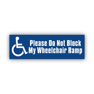 May include: A rectangular blue sign with white text and a wheelchair symbol. The sign reads "Please Do Not Block My Wheelchair Ramp". The wheelchair symbol is on the left side of the sign.