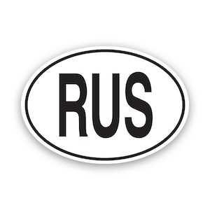 May include: An oval sticker in white, featuring the letters "RUS" in bold black font, with a black border. The sticker is designed for application to vehicles or other surfaces.
