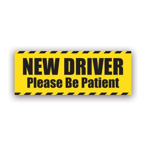 Puede incluir: Una señal de advertencia amarilla y negra con el texto "NEW DRIVER Please Be Patient".