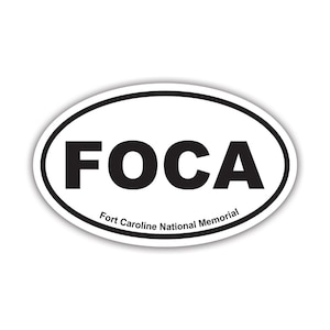 May include: An oval-shaped white sticker with a thick black border. The sticker features the large black text FOCA in the center, with the smaller black text Fort Caroline National Memorial printed in an arc along the bottom edge.