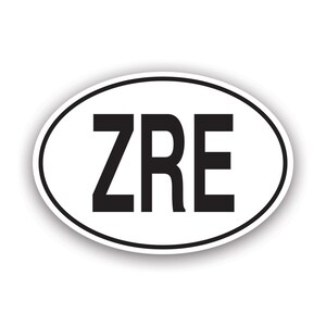 Può includere: Adesivo ovale bianco con bordo nero e le lettere "ZRE" in grassetto nero. L'adesivo ha una leggera ombra, che gli conferisce un aspetto tridimensionale. Il design è semplice e pulito.