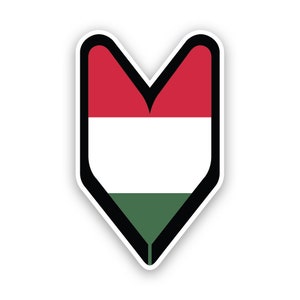 Può includere: Un adesivo con la bandiera ungherese. La bandiera è a forma di scudo rivolto verso il basso con un bordo nero. Presenta tre strisce orizzontali: rossa in alto, bianca al centro e verde in basso.