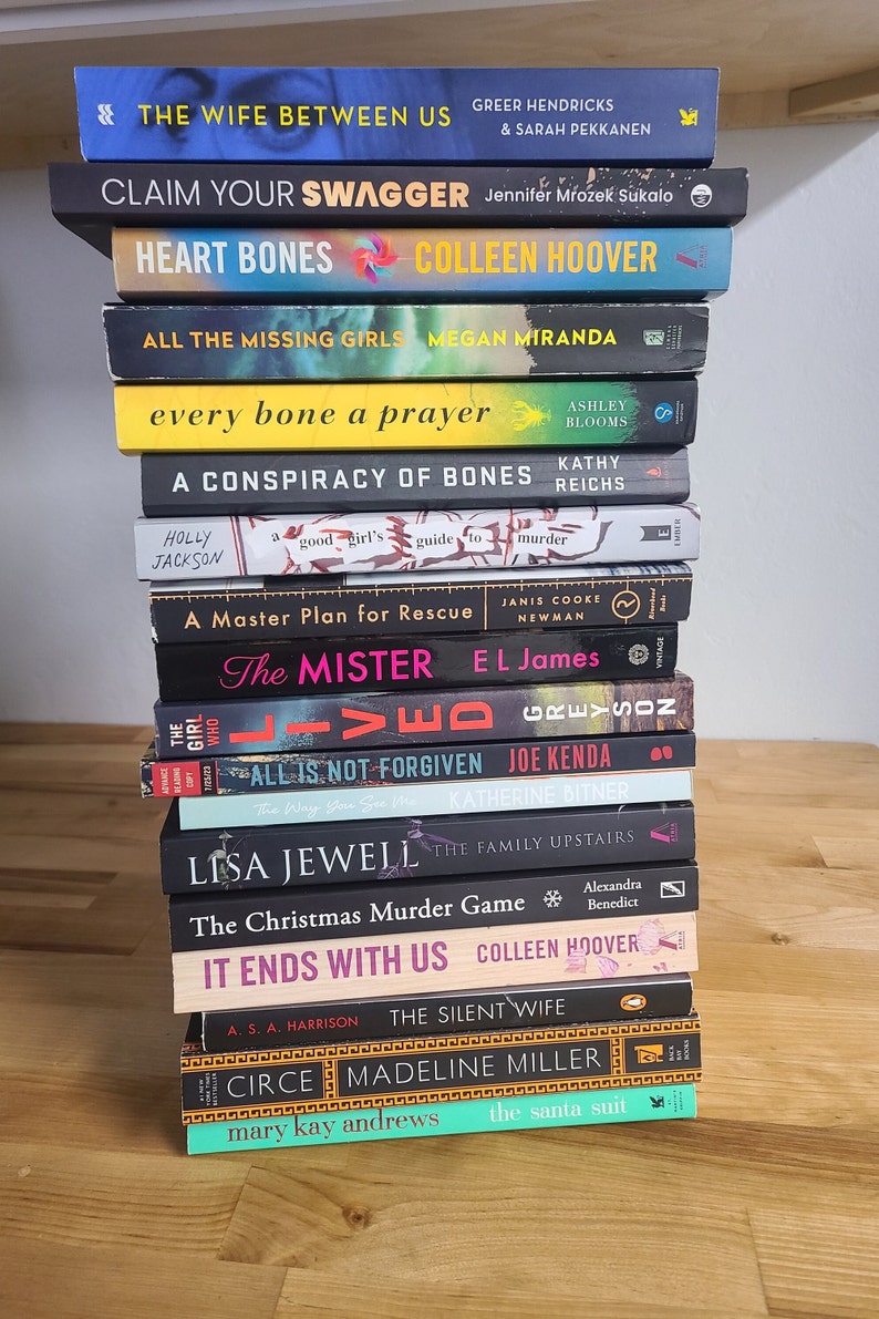 May include: A stack of 14 paperback books, mostly mystery and thriller novels, with titles like "The Wife Between Us", "Claim Your Swagger", "Heart Bones", "All the Missing Girls", "Every Bone a Prayer", "A Conspiracy of Bones", "The Mister", "All is Not Forgiven", "The Christmas Murder Game", "It Ends With Us", "The Silent Wife", "Circe", and "The Santa Suit".
