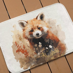 May include: A watercolor painting of a red panda cub with brown fur and white markings, looking directly at the viewer. The panda is surrounded by brown and green foliage and white flowers.