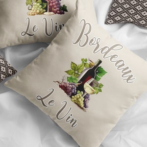 May include: Two beige throw pillows with the text "Bordeaux Le Vin" and a graphic of a bottle of wine, grapes, and a glass of wine.