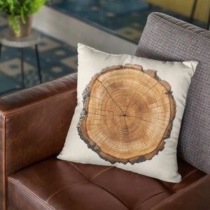 Könnte beinhalten: Ein braunes Ledersofa mit einem weißen Kissen mit Holzmaserung. Das Kissen liegt auf dem Sofa mit einem grauen Kissen dahinter.