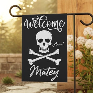 May include: Black welcome garden flag with a white skull and crossbones, the text "Welcome Matey" and the word "Arr!"