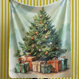 Puede incluir: Una manta con temática navideña con una ilustración en acuarela de un árbol de Navidad decorado con adornos y regalos envueltos. La manta se sostiene, mostrando el diseño. La paleta de colores incluye verdes, rojos y azules.