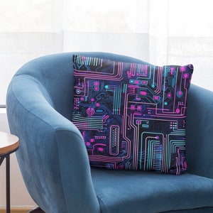 May include: A blue armchair with a throw pillow featuring a black, pink, and blue circuit board design. The armchair has a wooden frame and sits on a tiled floor.