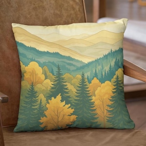 Puede incluir: Cojín cuadrado con diseño de paisaje. El cojín muestra una escena de bosque con árboles verdes y amarillos, colinas y un cielo amarillo. El cojín está colocado sobre una silla de cuero marrón.