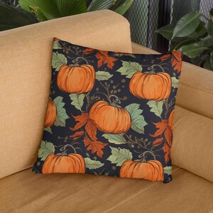 May include: A throw pillow with a dark blue background and a repeating pattern of orange pumpkins, green leaves, and brown branches.