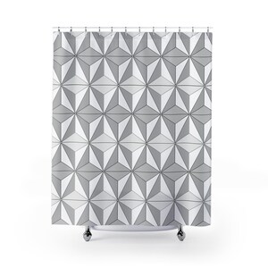 May include: A geometric shower curtain featuring a repeating pattern of three-dimensional star-like shapes in shades of gray and white. The curtain hangs from a metal rod with silver-colored rings and is designed to fit a standard-sized shower or bathtub.