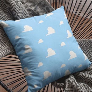 May include: A blue throw pillow with a white cloud pattern. The pillow is sitting on a black and gray chair.
