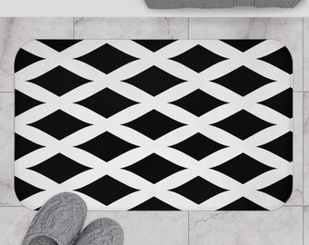 May include: Black and white geometric bath mat with a diamond pattern. The mat is on a tiled floor.