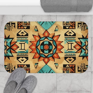 May include: A bath mat with a geometric pattern in shades of orange, blue, and brown. The pattern features a central sunburst design with a circle in the middle.