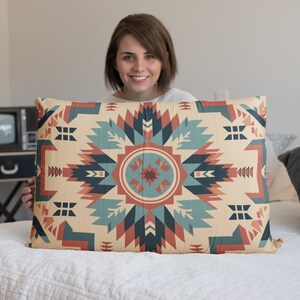 Op de afbeelding: Een decoratief kussen met een geometrisch patroon in tinten rood, blauw en beige. Het patroon heeft een centraal stervormig ontwerp met herhalende geometrische vormen.