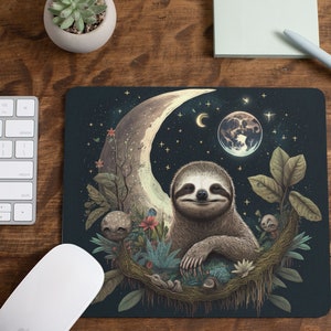 May include: A dark blue mouse pad with a crescent moon, stars, and a sloth sitting on a branch. The sloth is smiling and has a relaxed expression. The moon is glowing and has a planet in the background.