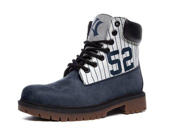 Peut inclure: Une botte montante avec une partie inférieure texturée bleu foncé et un panneau supérieur blanc à fines rayures verticales bleu marine. Le côté affiche le numéro 52 en bleu marine, tandis que la languette porte un logo NY bleu marine. Lacets noirs.