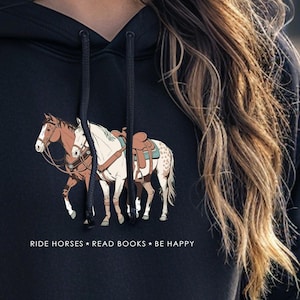 May include: Black hoodie featuring a graphic of two horses wearing saddles and the text "RIDE HORSES * READ BOOKS * BE HAPPY".
