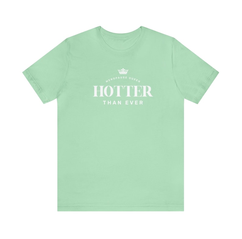 May include: A light green t-shirt with a white crown and the text "Menopause Queen" above the text "Hotter Than Ever".